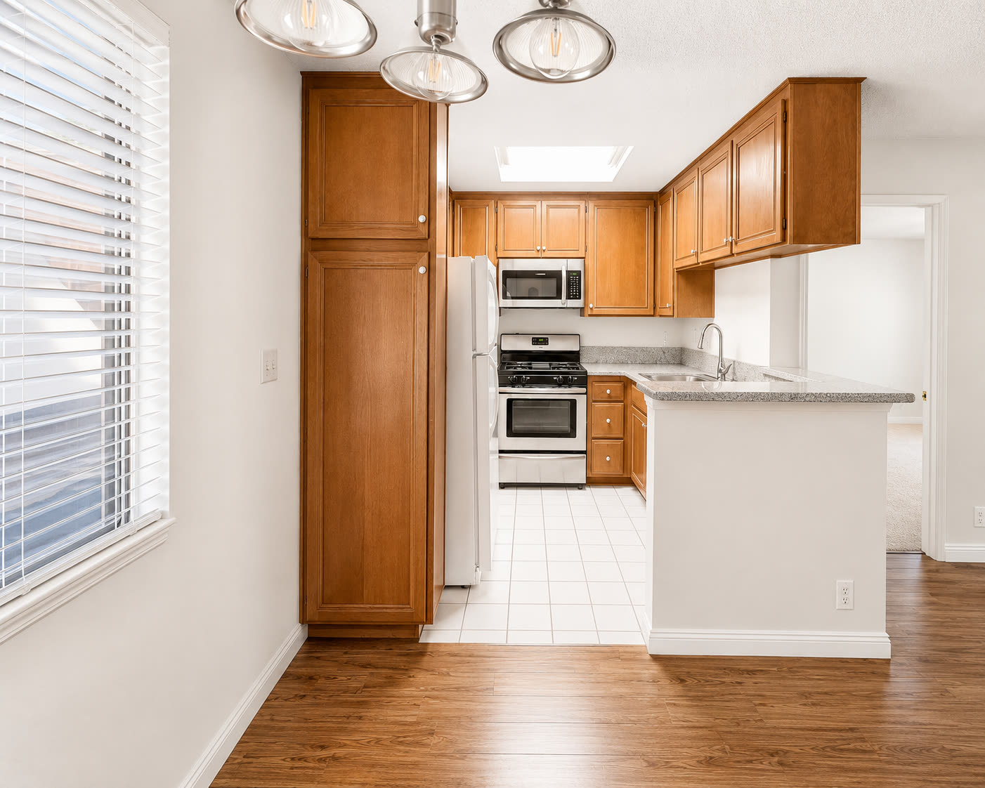 Kitchen with wood cabinetry, gas range, and skylight